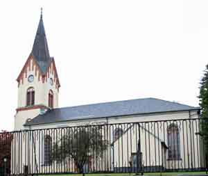 En kyrka med tornet åt vänster. Tornet takgaveldel är markerad med rödmålat trä
